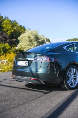 Notteroy, Norveç - 22 Ağustos 2021 Tesla model S P85 + arka planda İskandinav limanı olan elektrikli bir otomobil..