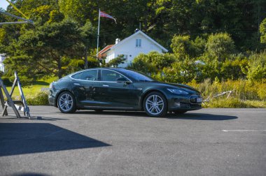 Notteroy, Norveç - 22 Ağustos 2021 Tesla model S P85 + arka planda İskandinav limanı olan elektrikli bir otomobil..