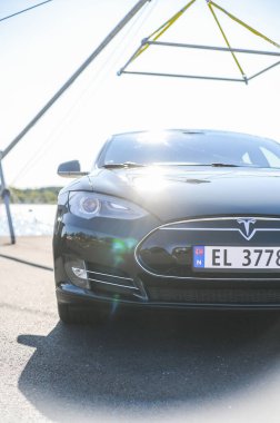 Notteroy, Norveç - 22 Ağustos 2021 Tesla model S P85 + arka planda İskandinav limanı olan elektrikli bir otomobil..