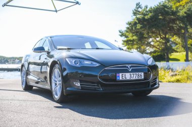 Notteroy, Norveç - 22 Ağustos 2021 Tesla model S P85 + arka planda İskandinav limanı olan elektrikli bir otomobil..