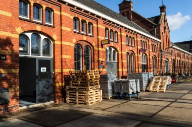 AMSTERDAM, NETHERLANDS 04, 2020: ZuiveringMarshal West 'in arkasındaki bir yığın palet ve diğer depolama malzemesi Amsterdam' daki eski bir fabrika