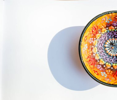 Beyaz arka planda soyut çiçeklerle süslenmiş yarım porselen bir kâse.