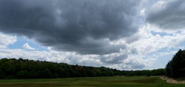 Kennermerduinen 'in açık sazlık alanlarının üzerinde dramatik ağır bulutlarla çekilmiş manzara..