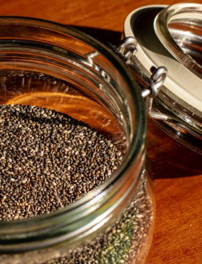 Kırmızı ahşap arka planda Chia tohumlarıyla dolu bir kavanozu kapat.