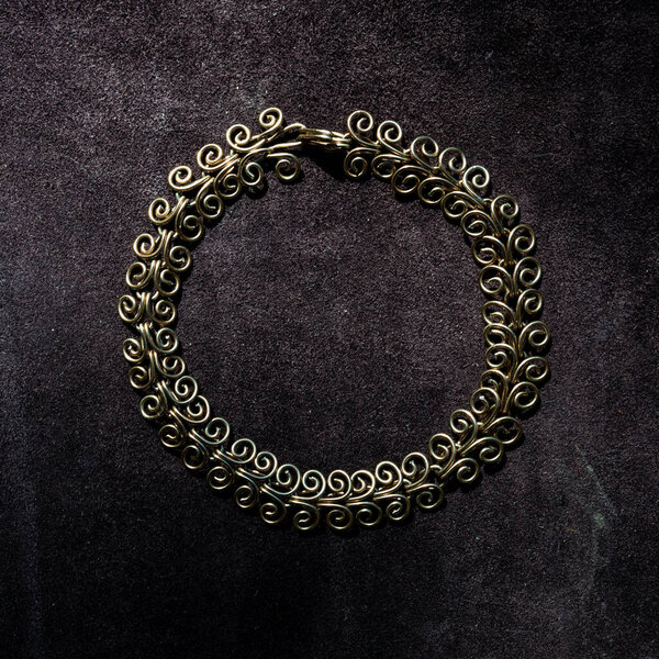 Handmade copper chain necklace on leather surface.