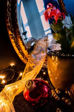 Kırmızı bir Noel mücevherinin, altın topların, dantel bir kurdelenin ve bir bitkinin durgun Noel hayatı.