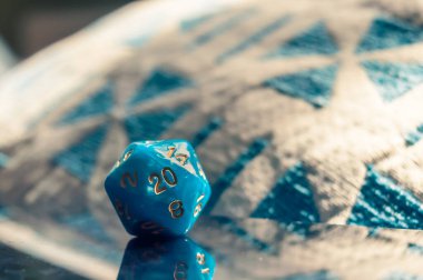 Su mavisi 20 kenarlı RPG 'nin yakın plan görüntüsü güneş ışığındaki yansıyan bir yüzeyde ölür.