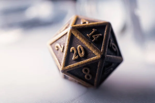 Close-up image of a metallic 20-sided die against a misty white background