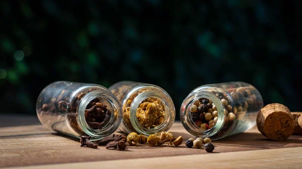 Image Three Glass Bottles Peppercorns Chamomile Cloves Spilling Out Wooden — Stock Photo, Image