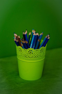 Yeşil zemin üzerinde açık yeşil camlı mavi kalemler, çizim araçları, okul malzemeleri, başbakanlık