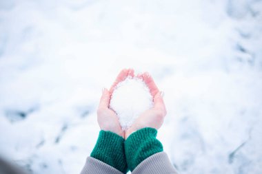 Eldivensiz bir kızın ellerinde kar, soğuk bir gün, kışın soğuktan kızarmış eller