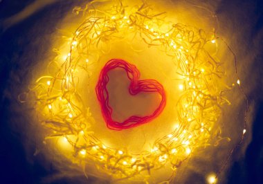 Çelengin içindeki kırmızı kalp, parlayan ışıklar, sevgililer günü, aşkın sembolü.