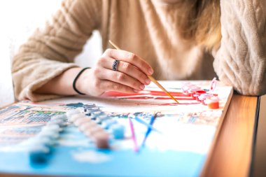 Yeni başlayanlar için resim yapan bir kadın, tuvale akrilik boya ile resim çizer, fırçayla resim yapar, bir kız resim çizer, kendini izole etme, ev hobisi, evde yaratıcılık, evde yaratıcılık, bir sanatçı resim çizer.