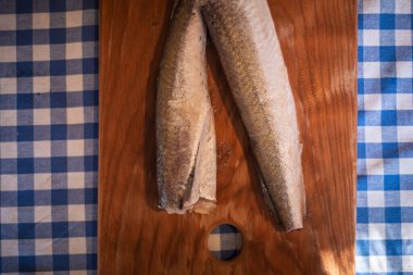 Tahtadaki çiğ balık, sağlıklı vejetaryen yiyecekler, mutfak tahtasındaki donmuş hake (Merluccius), balık pişirme