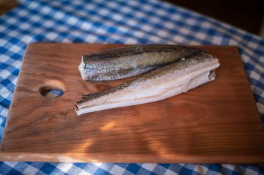Tahtadaki çiğ balık, sağlıklı vejetaryen yiyecekler, mutfak tahtasındaki donmuş hake (Merluccius), balık pişirme