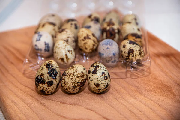 fresh quail eggs in a plastic box on a wooden board, quail eggs for a delicious Easter holiday in a tray, preparation for Easter, healthy dietary food, diet