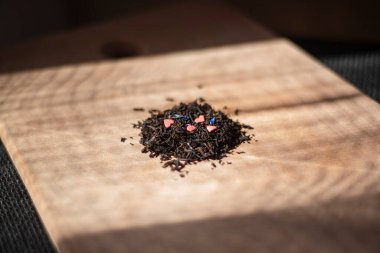 Tahta üzerinde pembe kalpler olan siyah çay, kuru aromalı içki, yakın plan bitki çayı.