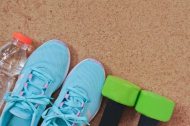 Fitness aletleri: spor ayakkabı, halter ve şişe suyu ahşap arka plan üzerinde 
