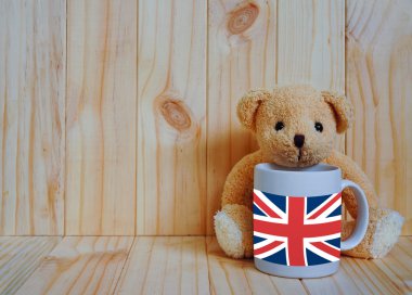 Oyuncak ayı ve ahşap arka plan ile bir fincan kahve İngiltere bayrağı. 
