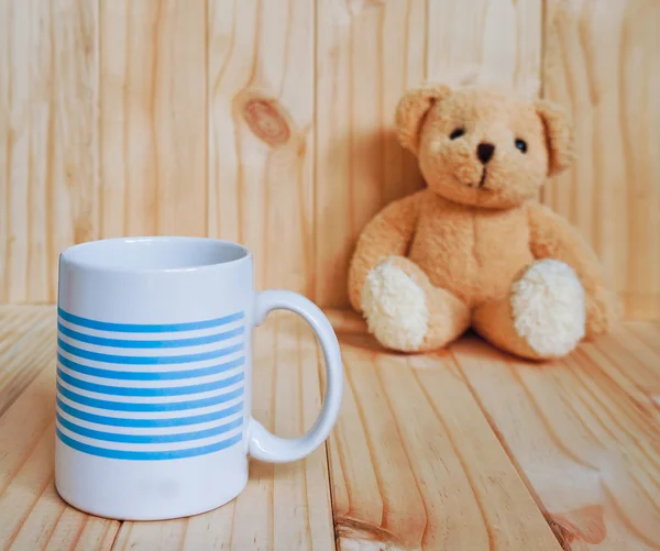 Secangkir kopi dengan boneka beruang dan latar belakang kayu. gaya vintage . — Stok Foto