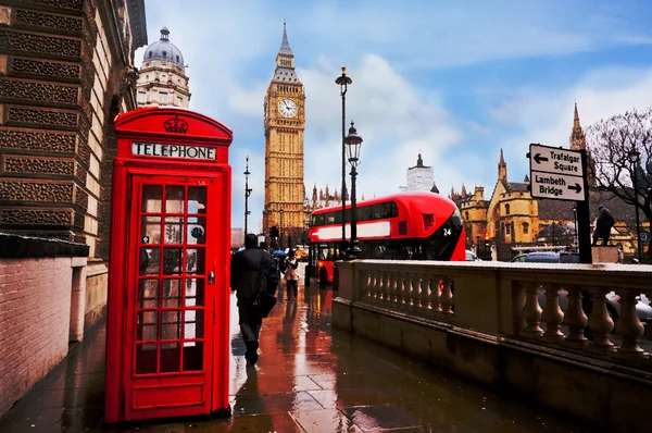 Tradizionale cabina telefonica rossa nel cielo blu dopo la pioggia giorno con il Big Ben e autobus rosso sullo sfondo Foto Stock