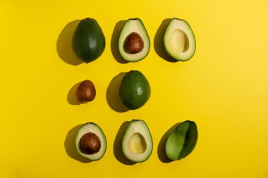 Sarı arka planda birden fazla avokado.