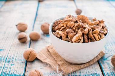 Ceviz kabukları ve bir kase boyalı beyaz ve mavi masada kırık fındık