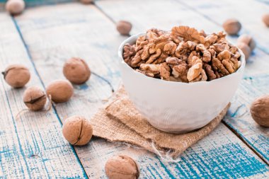 Ceviz kabukları ve bir kase boyalı beyaz ve mavi masada kırık fındık