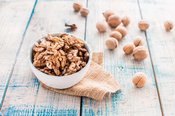 Ceviz kabukları ve bir kase boyalı beyaz ve mavi masada kırık fındık