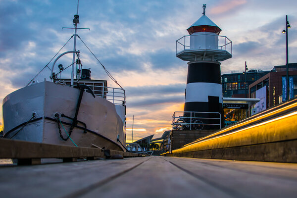 The lighthouse of Aker Brygge Embankment In City Center in Oslo, Norway in the evening with colorful sunset and illumination