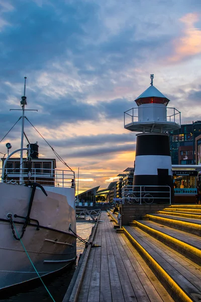 De vuurtoren van Aker Brygge Embankment In City Center in Oslo, Noorwegen in de avond met kleurrijke zonsondergang en verlichting — Stockfoto