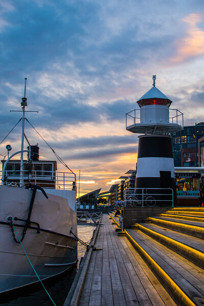 The lighthouse of Aker Brygge Embankment In City Center in Oslo, Norway in the evening with colorful sunset and illumination