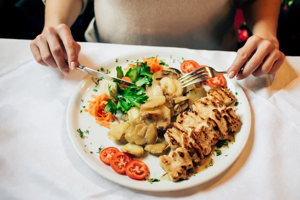Kız bir sebian restoranında: ızgara tavuk, patates ve sebzeler ile büyük tabak — Stok fotoğraf