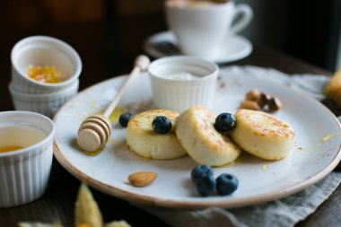 Mini cheesecakes, meyveler, fındık ve beyaz tabakta bal ile Servis Kahvaltı