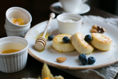 Mini cheesecakes, meyveler, fındık ve beyaz tabakta bal ile Servis Kahvaltı