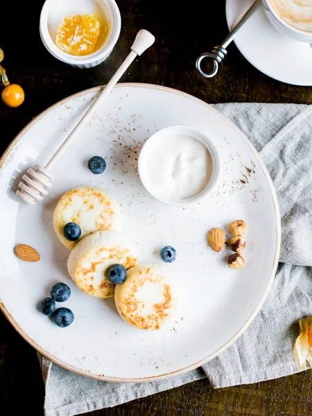 Śniadanie z mini Serniki, jagody, orzechy i miód na białym talerzu — Zdjęcie stockowe