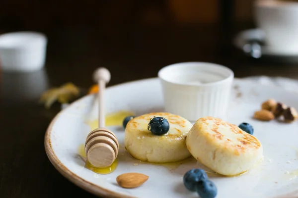 Mini cheesecakes, meyveler, fındık ve beyaz tabakta bal ile Servis Kahvaltı