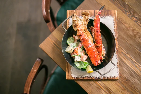 Yengeç falanks yukarıdan ahşap bir masa üzerinde metal tavada bir kenara salata ile