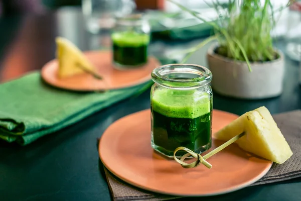 Wheatgrass juice with piece of pineapple on the plate in a restaurant — Stock Photo, Image