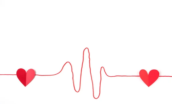 Sevgililer Günü için iplik çizgisine yerleştirilmiş iki kırmızı kağıt kalp beyaz arka planda izole edilmiş..