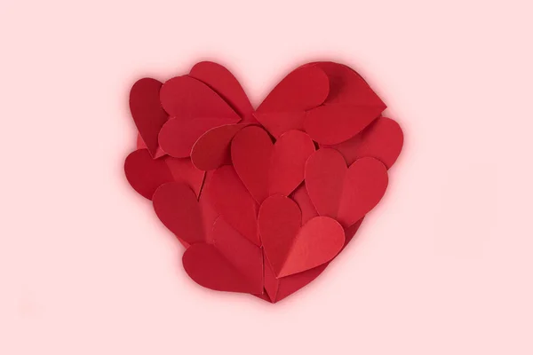 Sevgililer Günü için pembe arka planda kırmızı kalp kağıtları. Üst görünüm.