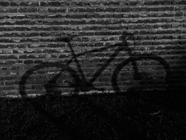 Tuğla bir duvarda siyah beyaz bir bisiklet gölgesi 