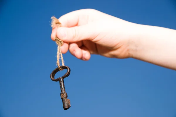 Mão de criança segurando uma chave velha em uma corda — Fotografia de Stock