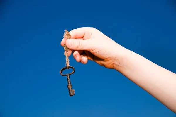 Child hand holding an old key on a string — Stock Photo, Image