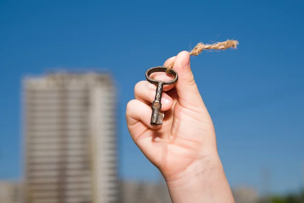 Child hand holding an old key on a string — Stock Photo, Image
