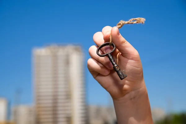 Child hand holding an old key on a string — Stock Photo, Image