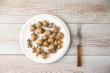 Meşe palamutları, tabak ve çatal masada
