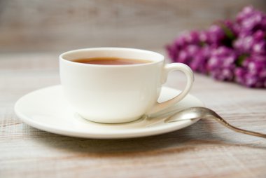 Bir fincan ve fincan tabağı masanın üzerinde bir içkiyle