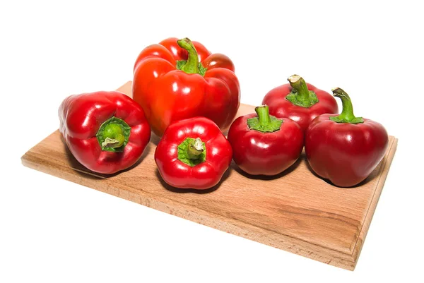 Several  peppers on a wooden cutting board. — Stock Photo, Image