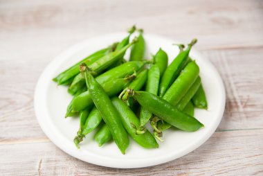 Büyük beyaz plaka üzerinde yeşil bezelye.